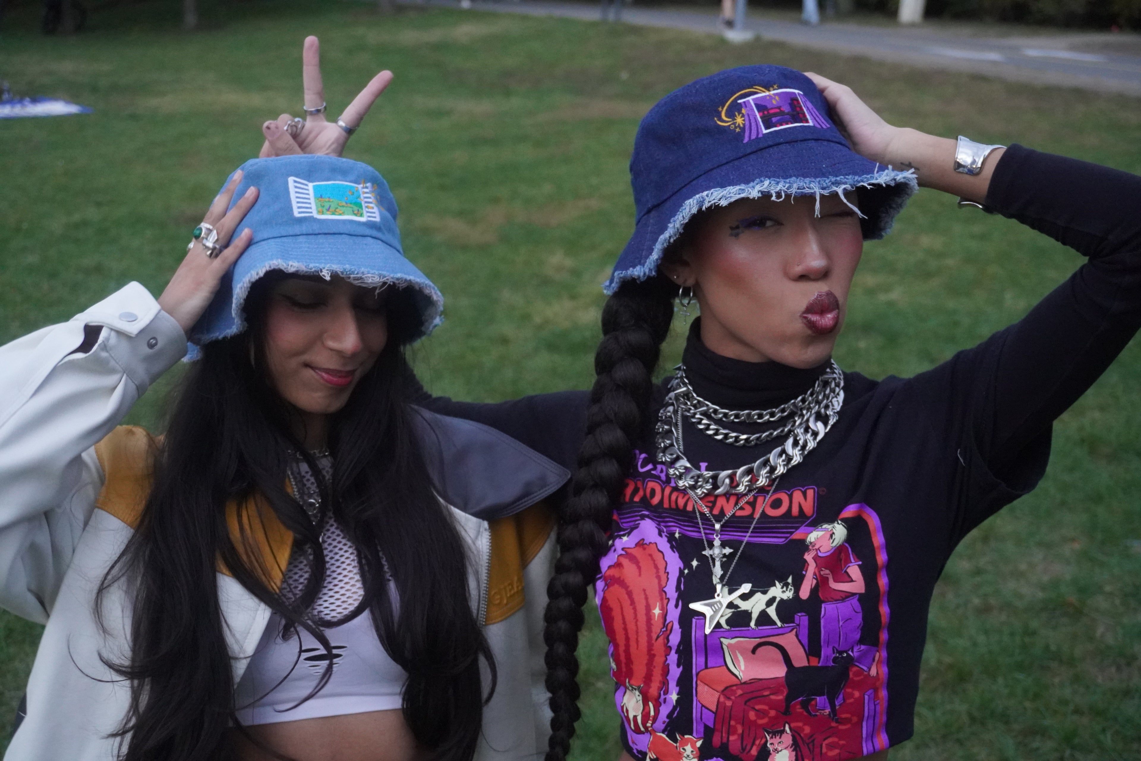 Two people wearing blue bucket hats outdoors in a grassy area