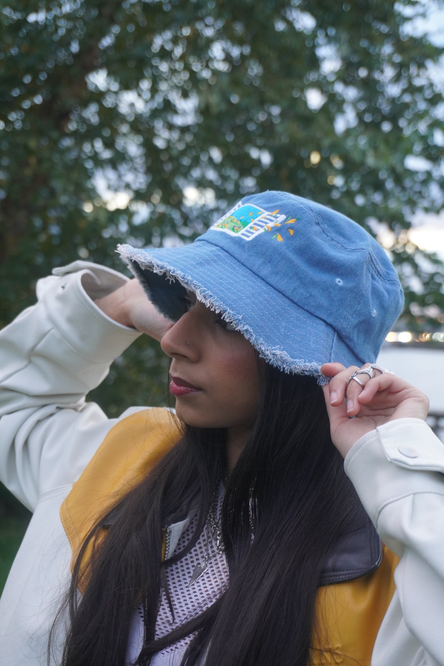 Person wearing a blue denim bucket hat with a blurred tree in the background